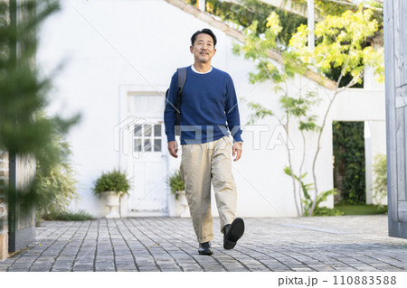 リュックを肩にかけて歩く笑顔の50代の男性  リュックを肩にかけて歩く笑顔の50代の男性  110883588