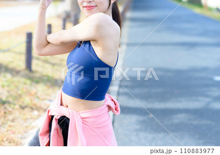 運動前にストレッチする若い女性　ボディメイク　ランニングウェア　スポーツブラ　顔無しトリミングアップ 110883977