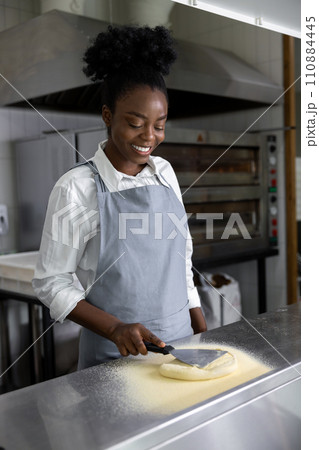 African american young woman preparing pizza in pizzeria kitchen 110884445