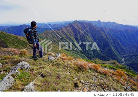 ピラミッド峰山頂からの日高山脈南部を眺める登山者 110884849