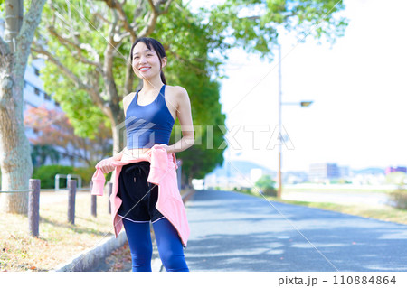 運動で痩せた体とお腹を見せる若い女性　ボディメイク　ダイエット　ランニングウェア　スポーツブラ 110884864