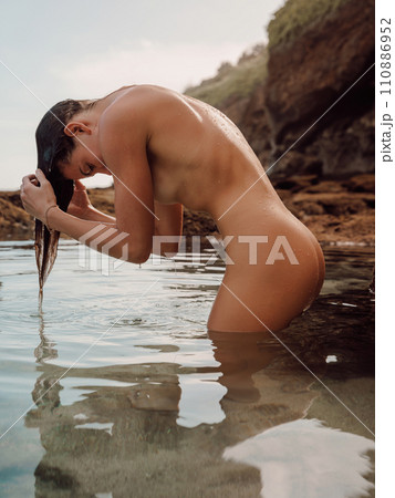 Portrait of woman with wet body in ocean water. Woman wringing out wet hair Portrait of woman with wet body in ocean water. Woman wringing out wet hair 110886952