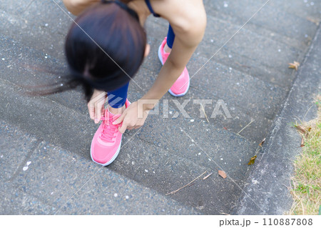 野外で運動中に階段で靴紐を結ぶ若い女性 ボディメイク レギンス 野外で運動中に階段で靴紐を結ぶ若い女性 ボディメイク レギンス 110887808
