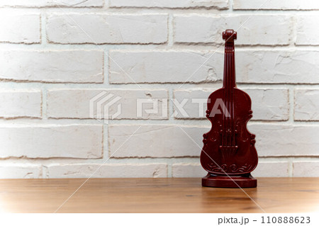 a wooden table with decorative violin on the background of a light brick wall 110888623