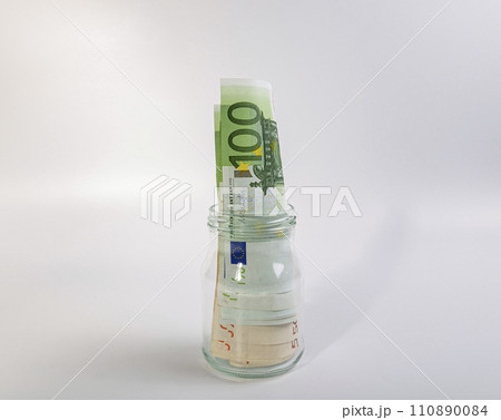 EURO bills in a glass jar, on a white background. Finance and business concept EURO bills in a glass jar, on a white background. Finance and business concept 110890084
