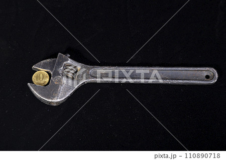 Allegory of the global financial crisis - Iron 10 rubles coin (written ten rubles, Bank of Russia in the Russian) in the grip of economic crisis, on a black background. Finance and business concept 110890718