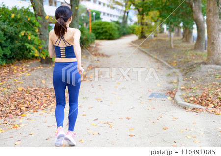 公園をジョギングする若い女性の後ろ姿　ダイエット　ボディメイク　ランニングウェア　スポーツブラ 110891085