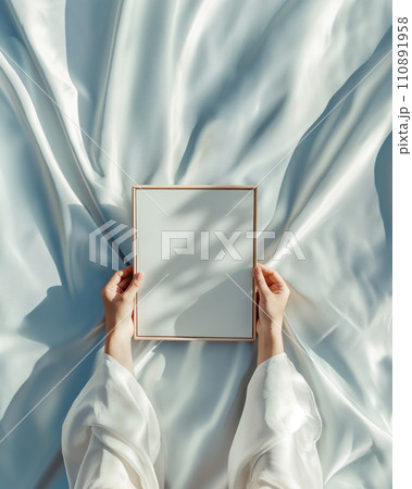 Hands holding blank white poster frame mock up template, interior in fusion style with light blue cover under the light and shadow 110891958