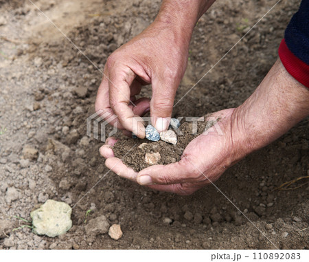 Male hands choose stones from the ground Male hands choose stones from the ground 110892083