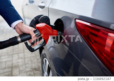 Closeup of unrecognizable businessman refueling gas tank of black luxury car 110892187