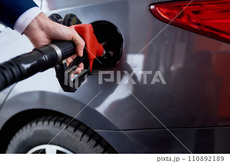Close up of male hand refueling gas tank of black luxury car at gas station, copy space 110892189