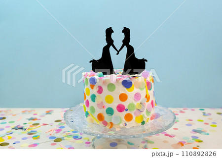 Two brides cake toppers on wedding cake with confetti. Lesbian wedding Two brides cake toppers on wedding cake with confetti. Lesbian wedding 110892826