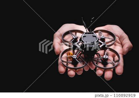 woman holds a racing drone in her hands, showing it to the camera on her palm. Close-up of a hobby toy woman holds a racing drone in her hands, showing it to the camera on her palm. Close-up of a hobby toy 110892919