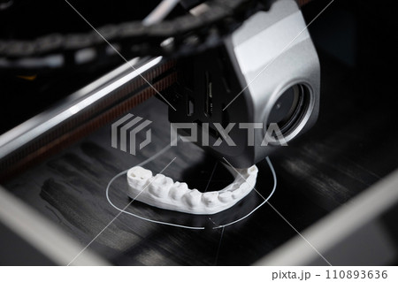 Macro shot of 3D printer extruder producing white-colored human lower jaw bone sample in engineering laboratory Macro shot of 3D printer extruder producing white-colored human lower jaw bone sample in engineering laboratory 110893636