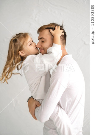 The daughter gently kisses Dad on the nose. A child in strong male hands. Father's Day 110893889