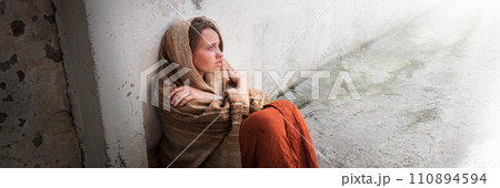 A girl in poor clothes sits on the ground A girl in poor clothes sits on the ground 110894594