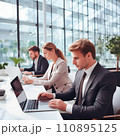 Businesspeople working on a laptops in an office with white walls, wide windows, dressed according to the business dress code and focused on work 110895125