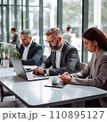 Businesspeople working on a laptops in an office with white walls, wide windows, dressed according to the business dress code and focused on work 110895127