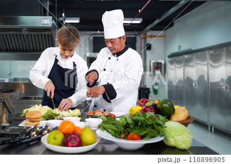 Chef teacher teaches cooking to the group children in class kitchen room.  110896905