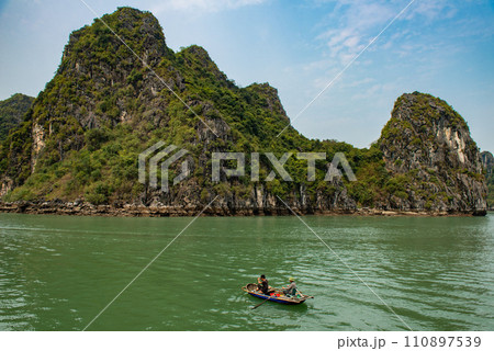 Vietnamese fisherman with beautiful island landscape of Halong Bay the UNESCO world heritage site in Vietnam. The bay features thousands of limestone karsts in various shapes and sizes. 110897539
