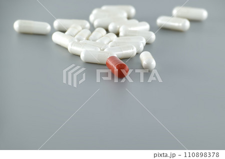 Medical capsule pills scattered on gray surface Medical capsule pills scattered on gray surface 110898378