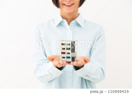 マンションの住宅模型を持って微笑むミドル女性 110898429