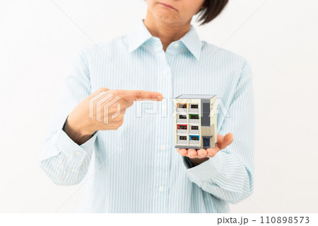 マンションの住宅模型を持って悩むミドル女性 110898573