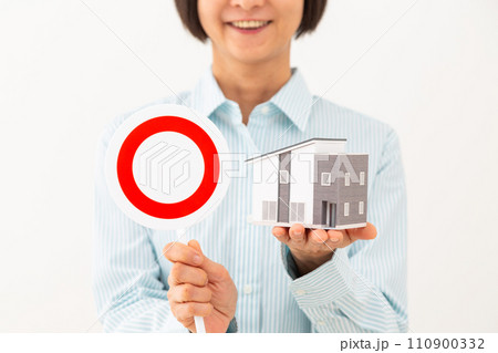 住宅模型と丸サインのプレートを持つ笑顔のミドル女性 住宅模型と丸サインのプレートを持つ笑顔のミドル女性 110900332
