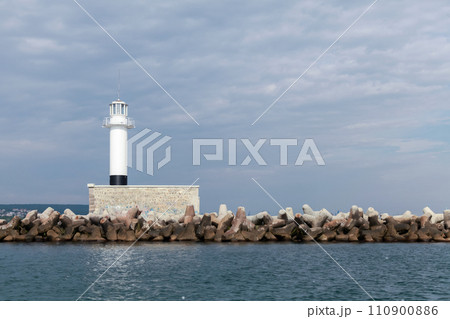 Breakwater with white lighthouse tower 110900886