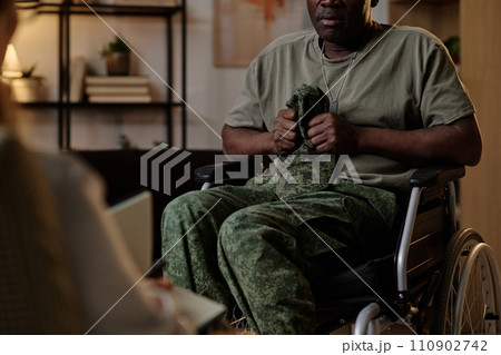 Black war veteran with PTSD firmly holding his uniform headwear at session with psychologist 110902742