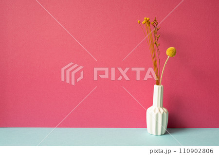 Vase of yellow dry flowers on skyblue table. pink wall background Vase of yellow dry flowers on skyblue table. pink wall background 110902806