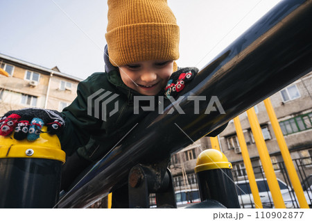 happy child kid boy plays on the horizontal bars on the playground in park in autumn 110902877