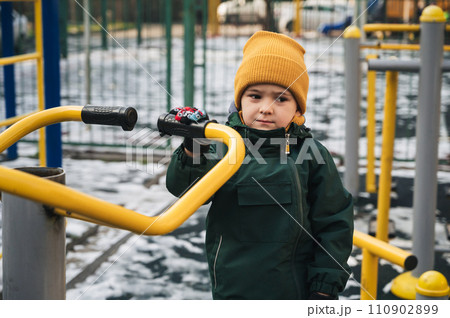 Sad lonely child kid boy playing on playground alone in park in winter Sad lonely child kid boy playing on playground alone in park in winter 110902899