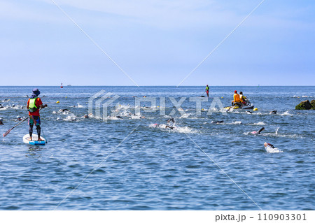 力泳するトライアスロン大会スイム競技者と大会スタッフ 110903301
