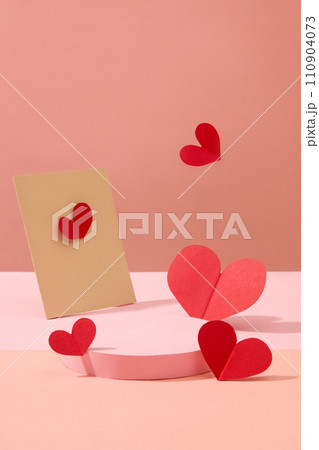 Front view of an empty podium decorated with paper card and red paper hearts on a sweet pink background. Blank space for display product. Minimalist concept for women day decoration  110904073