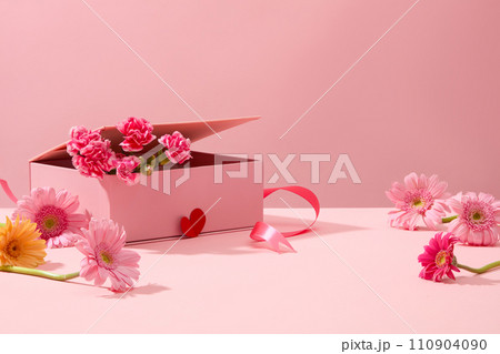 Cute pink background with gerberas and fresh carnations decorated. Sweet and romantic women day decoration ideas. Empty space for product presentation, front view 110904090
