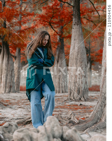 Woman walking down the park among tacsodium trees. Woman walking down the park among tacsodium trees. 110904456