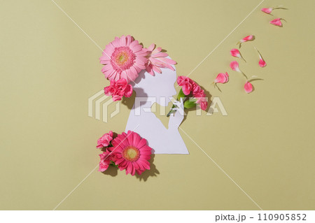 A woman made of paper decorated against pastel background with a lot of flowers and petals. The flowers are arranged as if the woman is holding a bouquet and the petals are flying A woman made of paper decorated against pastel background with a lot of flowers and petals. The flowers are arranged as if the woman is holding a bouquet and the petals are flying 110905852