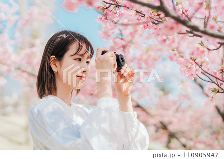 桜の写真を撮る若い女性 110905947