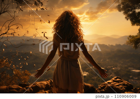 Young woman with long hair fluttering in the wind at sunset the sun in the field with her back 110906009