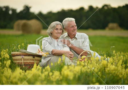 Senior nice couple sitting on the grass in the field Senior nice couple sitting on the grass in the field 110907045