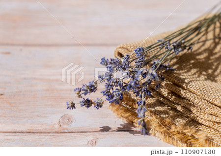 Dried lavender flowers on burlap textile material on wooden background. Copy space for your text. Advertisement mock up 110907180