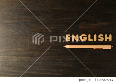 The word "English" and a notebook, the concept of learning English, on a dark background. 110907543
