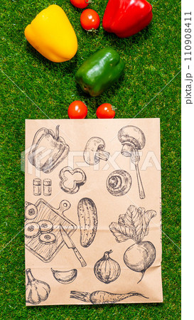 a paper bag lies on the green grass with fruits and vegetables around, moss, mock up 110908411