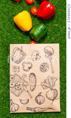 a paper bag lies on the green grass with fruits and vegetables around, moss, mock up 110908415