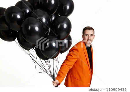 happy man in orange jacket with black air balloons on white background. birthday party 110909432