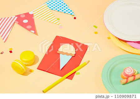 Pastel background decorated with cards, macarons, colored plates and confetti. Colorful and creative space. Homemade gifts with colored paper. 110909871