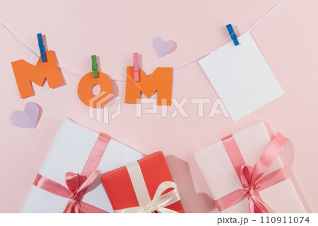 Gift boxes, MOM letters, paper hearts and blank cards are displayed on a pastel background. Space for writing wishes to mother on women day or mother day. Gift boxes, MOM letters, paper hearts and blank cards are displayed on a pastel background. Space for writing wishes to mother on women day or mother day. 110911074