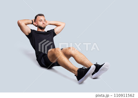 Focused handsome strong young caucasian man with beard in sportswear make exercises for abs 110911562