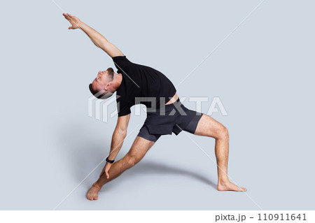 Calm young caucasian man with beard in sportswear practice yoga, stretching body 110911641
